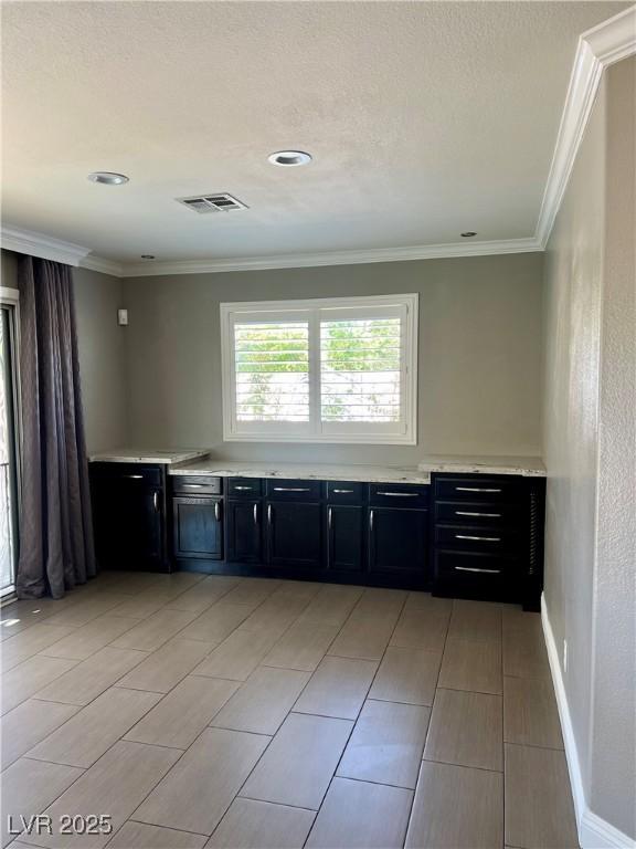 1921 Moonlight Bluff Ave, North Las Vegas, NV 89084 - kitchen with dark cabinetry, light countertops, and crown molding
