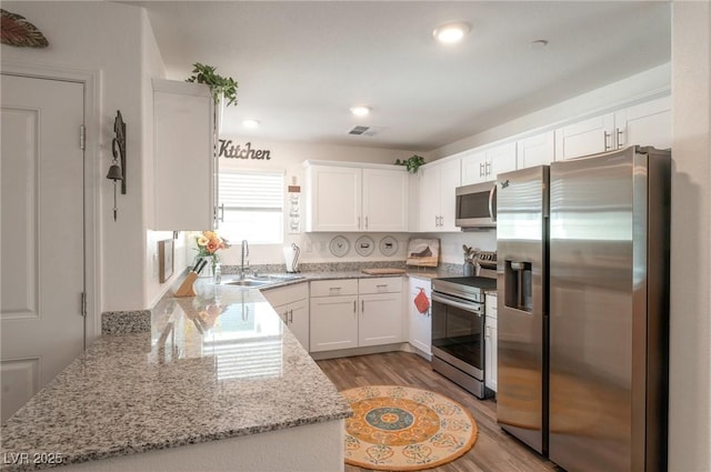 12348 Golden Wreath Rd Unit 1, Las Vegas, NV 89183 - kitchen with appliances with stainless steel finishes, a sink, white cabinetry, light stone counters, and recessed lighting