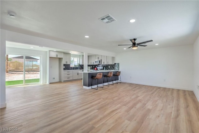 5200 Blanton Dr, Las Vegas, NV 89122 - kitchen with a breakfast bar, stainless steel microwave, decorative backsplash, recessed lighting, and a ceiling fan