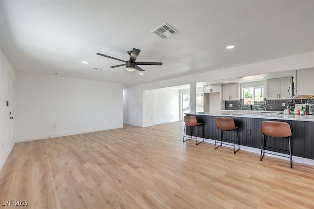5200 Blanton Dr, Las Vegas, NV 89122 - kitchen with a breakfast bar, recessed lighting, tasteful backsplash, light wood-type flooring, and a peninsula