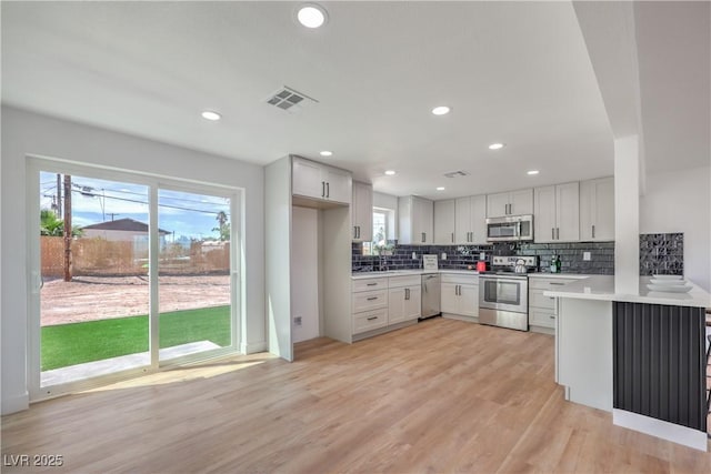 5200 Blanton Dr, Las Vegas, NV 89122 - kitchen with stainless steel appliances, light wood-type flooring, decorative backsplash, light countertops, and healthy amount of natural light