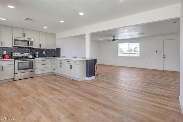 5200 Blanton Dr, Las Vegas, NV 89122 - kitchen with stainless steel appliances, open floor plan, a peninsula, light countertops, and decorative backsplash