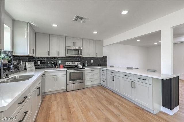 5200 Blanton Dr, Las Vegas, NV 89122 - kitchen featuring appliances with stainless steel finishes, a sink, a peninsula, backsplash, and light wood finished floors