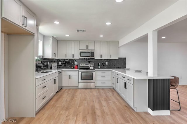 5200 Blanton Dr, Las Vegas, NV 89122 - kitchen with appliances with stainless steel finishes, a peninsula, a sink, tasteful backsplash, and a breakfast bar area
