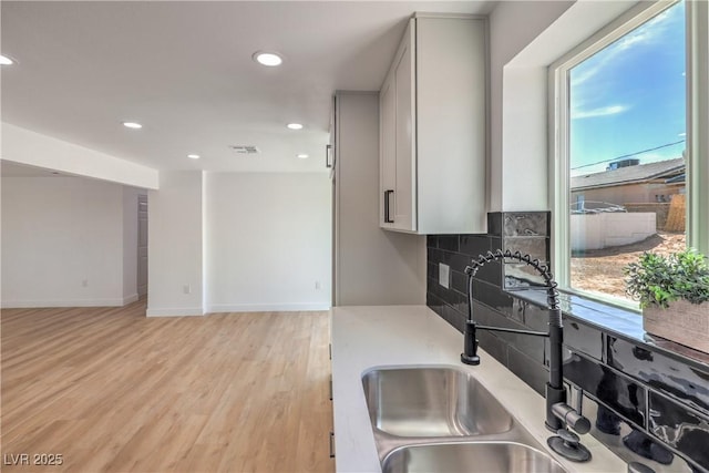 5200 Blanton Dr, Las Vegas, NV 89122 - kitchen featuring recessed lighting, a sink, light wood-style flooring, backsplash, and light countertops