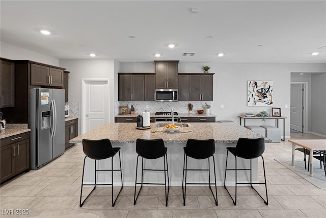 5234 Savannah Rose St, Las Vegas, NV 89149 - kitchen with appliances with stainless steel finishes, decorative backsplash, dark brown cabinetry, light stone counters, and recessed lighting