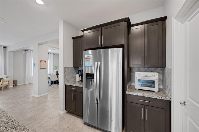 5234 Savannah Rose St, Las Vegas, NV 89149 - kitchen with stainless steel fridge, tasteful backsplash, dark brown cabinetry, light stone countertops, and baseboards
