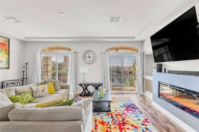 5889 Thistle Meadow Ave, Las Vegas, NV 89139 - living room featuring wood finished floors, healthy amount of natural light, and a glass covered fireplace