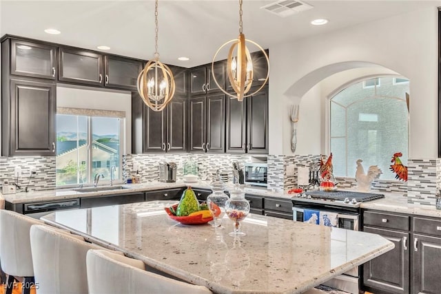 5889 Thistle Meadow Ave, Las Vegas, NV 89139 - kitchen with light stone counters, a breakfast bar area, backsplash, and recessed lighting
