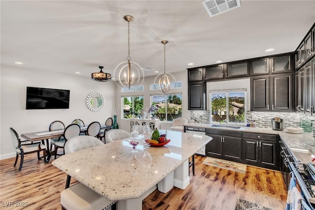 5889 Thistle Meadow Ave, Las Vegas, NV 89139 - kitchen featuring a chandelier, backsplash, appliances with stainless steel finishes, light stone counters, and a kitchen island