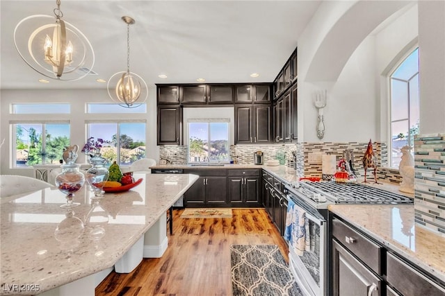 5889 Thistle Meadow Ave, Las Vegas, NV 89139 - kitchen featuring a chandelier, stainless steel appliances, light wood finished floors, tasteful backsplash, and pendant lighting