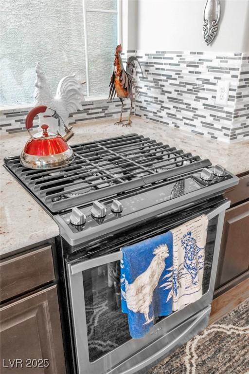 5889 Thistle Meadow Ave, Las Vegas, NV 89139 - kitchen view of stainless steel gas range oven, decorative backsplash, and light stone counters