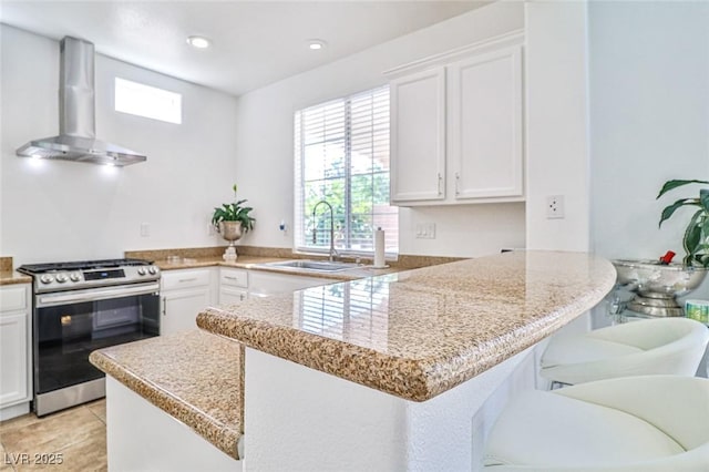 10667 Olympic Pine Dr, Las Vegas, NV 89135 - kitchen with stainless steel range with gas cooktop, wall chimney exhaust hood, a sink, a peninsula, and white cabinetry