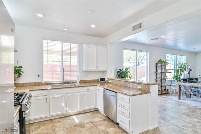 10667 Olympic Pine Dr, Las Vegas, NV 89135 - kitchen featuring appliances with stainless steel finishes, open floor plan, a peninsula, white cabinetry, and a sink