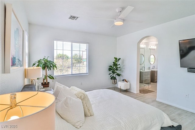 10667 Olympic Pine Dr, Las Vegas, NV 89135 - bedroom featuring arched walkways, light wood-style flooring, baseboards, connected bathroom, and ceiling fan