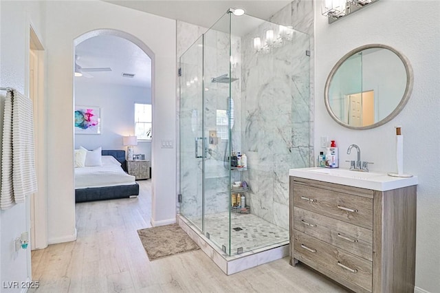 10667 Olympic Pine Dr, Las Vegas, NV 89135 - bathroom featuring a marble finish shower, wood finished floors, vanity, ceiling fan, and connected bathroom