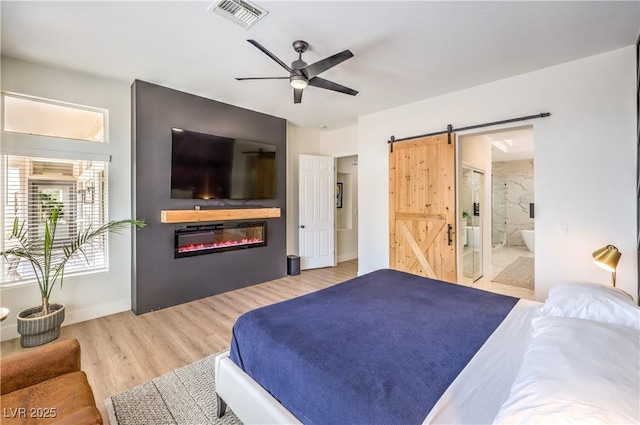 3028 Treesdale Dr, Las Vegas, NV 89134 - bedroom with a barn door, wood finished floors, a glass covered fireplace, connected bathroom, and baseboards