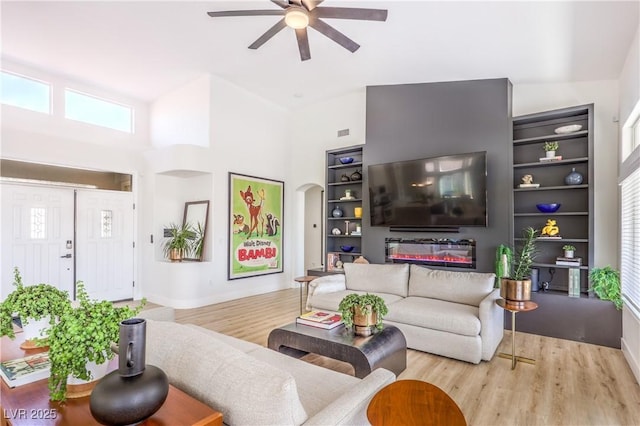 3028 Treesdale Dr, Las Vegas, NV 89134 - living room featuring ceiling fan, plenty of natural light, built in shelves, wood finished floors, and a high ceiling