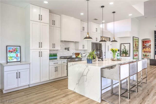 3028 Treesdale Dr, Las Vegas, NV 89134 - kitchen with light wood-style flooring, tasteful backsplash, light stone counters, white cabinetry, and recessed lighting