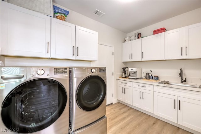 3028 Treesdale Dr, Las Vegas, NV 89134 - laundry room featuring washing machine and dryer, light wood finished floors, and cabinet space