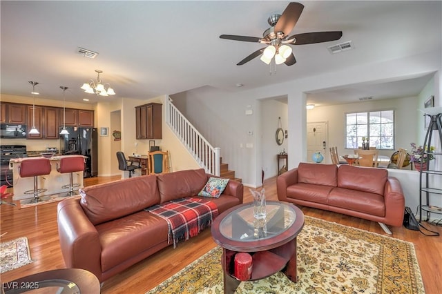10353 Yew Blossom Ave, Las Vegas, NV 89166 - living room featuring stairs, light wood-style flooring, a chandelier, and a ceiling fan