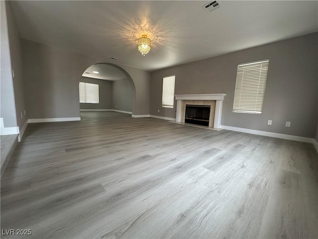 3340 Shallow Pond Dr, Las Vegas, NV 89117 - unfurnished living room with a premium fireplace, baseboards, wood finished floors, arched walkways, and a chandelier