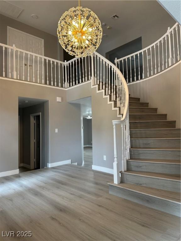 3340 Shallow Pond Dr, Las Vegas, NV 89117 - staircase featuring baseboards, a towering ceiling, wood finished floors, and a chandelier