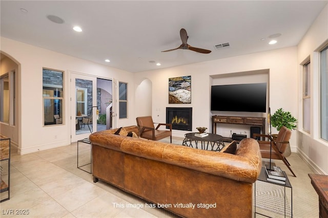 8 Laricola Ct, Henderson, NV 89011 - living room with arched walkways, a glass covered fireplace, a ceiling fan, recessed lighting, and baseboards