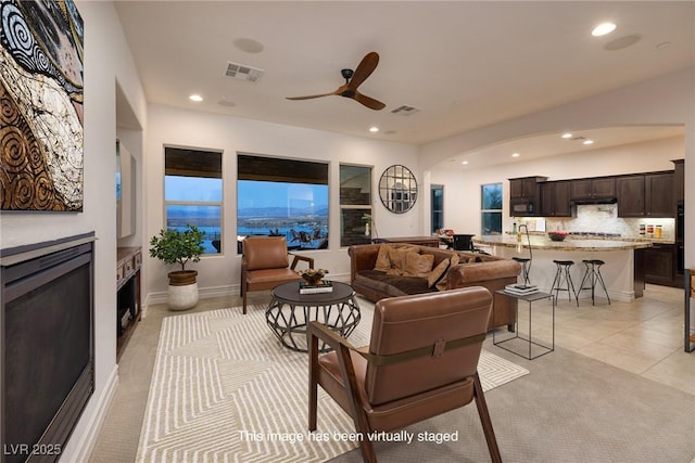 8 Laricola Ct, Henderson, NV 89011 - living room with arched walkways, a ceiling fan, recessed lighting, a glass covered fireplace, and light tile patterned floors