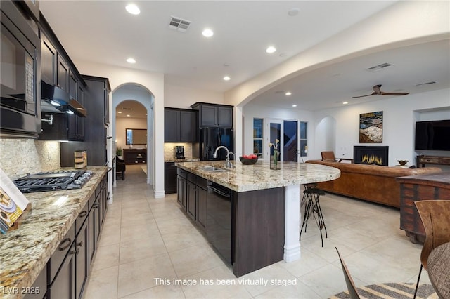 8 Laricola Ct, Henderson, NV 89011 - kitchen with black appliances, arched walkways, recessed lighting, under cabinet range hood, and light stone countertops