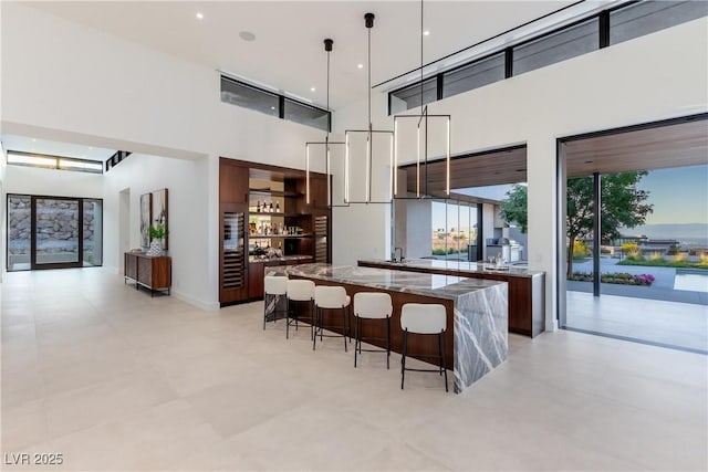 6 Rockmount Ct, Henderson, NV 89012 - kitchen featuring modern cabinets, a towering ceiling, a kitchen bar, a large island, and stone counters