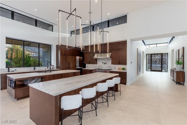 6 Rockmount Ct, Henderson, NV 89012 - kitchen featuring modern cabinets, a spacious island, a high ceiling, a sink, and under cabinet range hood
