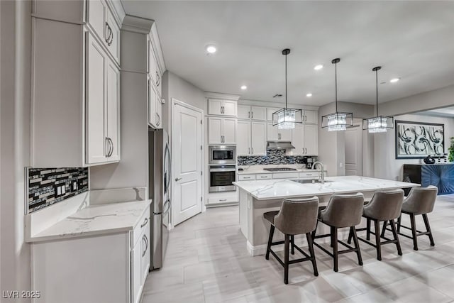 101 Mirage View Dr, Henderson, NV 89011 - kitchen featuring stainless steel appliances, a sink, a breakfast bar, tasteful backsplash, and a large island with sink