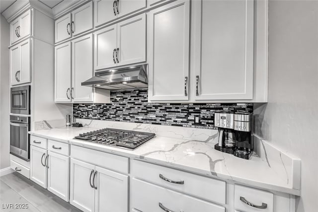 101 Mirage View Dr, Henderson, NV 89011 - kitchen with stainless steel appliances, under cabinet range hood, decorative backsplash, light stone countertops, and white cabinetry