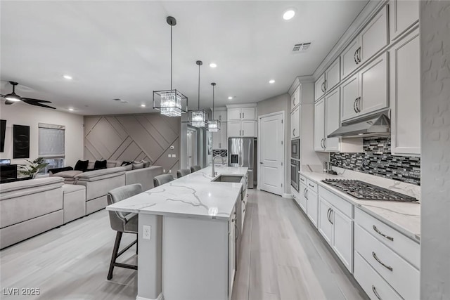101 Mirage View Dr, Henderson, NV 89011 - kitchen featuring under cabinet range hood, appliances with stainless steel finishes, a kitchen breakfast bar, light wood-type flooring, and recessed lighting
