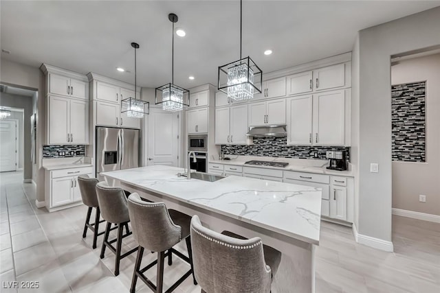 101 Mirage View Dr, Henderson, NV 89011 - kitchen with stainless steel appliances, a sink, decorative backsplash, a center island with sink, and baseboards