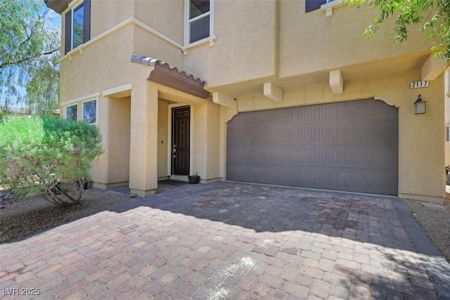 2117 Leatherbridge Ct, North Las Vegas, NV 89081 - view of exterior entry with a garage, stucco siding, decorative driveway, and a tile roof