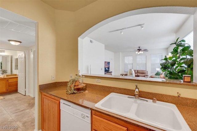 10001 Peace Way Unit 1250, Las Vegas, NV 89147 - kitchen with white dishwasher, a sink, arched walkways, a ceiling fan, and brown cabinetry