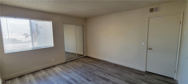 3151 Soaring Gulls Dr Unit 2058, Las Vegas, NV 89128 - unfurnished bedroom featuring wood finished floors, a textured ceiling, a closet, and baseboards