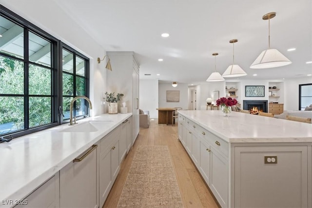 204 Canyon Dr, Las Vegas, NV 89107 - kitchen featuring open floor plan, a sink, light wood-style floors, pendant lighting, and white cabinetry
