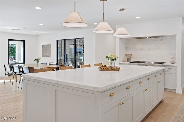 204 Canyon Dr, Las Vegas, NV 89107 - kitchen with a kitchen island, light wood-style flooring, hanging light fixtures, recessed lighting, and light stone countertops