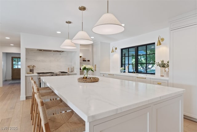 204 Canyon Dr, Las Vegas, NV 89107 - kitchen featuring white cabinetry, light wood-style flooring, a center island, recessed lighting, and hanging light fixtures