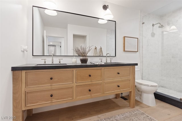 204 Canyon Dr, Las Vegas, NV 89107 - bathroom featuring double vanity, toilet, tiled shower, and wood finished floors