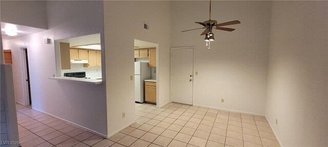 2216 Short Pine Dr, Las Vegas, NV 89108 - kitchen featuring freestanding refrigerator, under cabinet range hood, ceiling fan, stove, and a towering ceiling