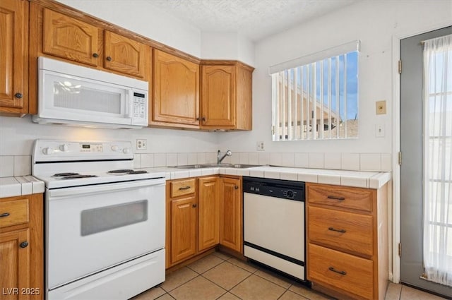 460 Crestway Rd, Henderson, NV 89015 - kitchen featuring white appliances, light tile patterned floors, a sink, brown cabinetry, and a textured ceiling
