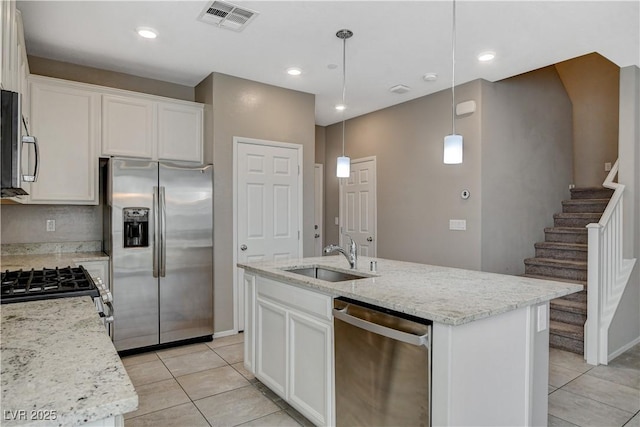 8486 Insignia Ave Unit 101, Las Vegas, NV 89178 - kitchen with stainless steel appliances, a sink, light tile patterned flooring, white cabinetry, and light stone counters