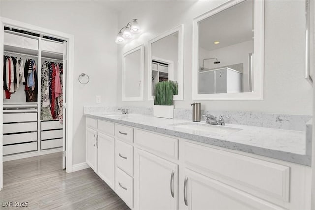 11856 Barona Mesa Ave, Las Vegas, NV 89138 - bathroom featuring a shower stall, double vanity, a walk in closet, and wood finished floors