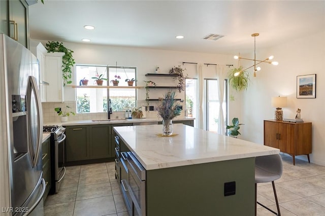 2021 Pelican Sky Beach Ave, North Las Vegas, NV 89081 - kitchen featuring appliances with stainless steel finishes, a sink, a kitchen island, tasteful backsplash, and light tile patterned floors
