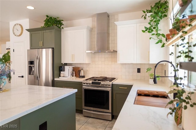 2021 Pelican Sky Beach Ave, North Las Vegas, NV 89081 - kitchen with stainless steel appliances, wall chimney exhaust hood, light stone counters, white cabinetry, and backsplash