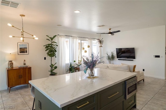 2021 Pelican Sky Beach Ave, North Las Vegas, NV 89081 - kitchen with stainless steel microwave, light tile patterned flooring, open floor plan, and a kitchen island